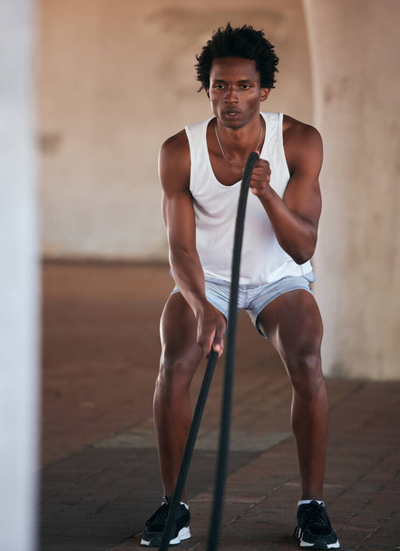 Exercise, fitness and black man with battle ropes for training workout in the city outdoors. Sports, energy and male body builder or athlete with heavy rope for strength, power or health in street - Photo, Image