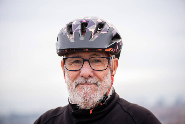Porträt eines älteren Mannes mit Helm und lächelnder Fahrradbekleidung - Foto, Bild
