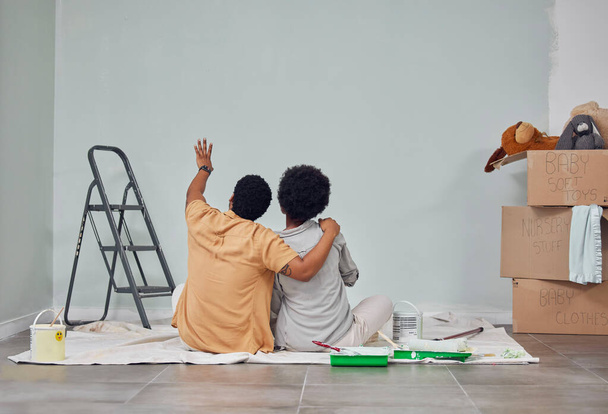 Planning, wall or black couple pointing in home renovation, diy or house remodel together on floor. Back view, painting or African man loves talking or working with teamwork in decoration with woman. - 写真・画像