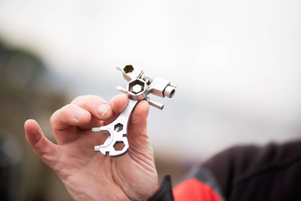 hand detail with tool for emergency bicycle repair, equipped with cyclist out of focus. - Photo, image