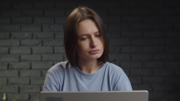 The female freelancer turns her head to the laptop and starts smiling after reading the email. A brunette works remotely at a laptop and reads email. High quality 4k footage - Séquence, vidéo