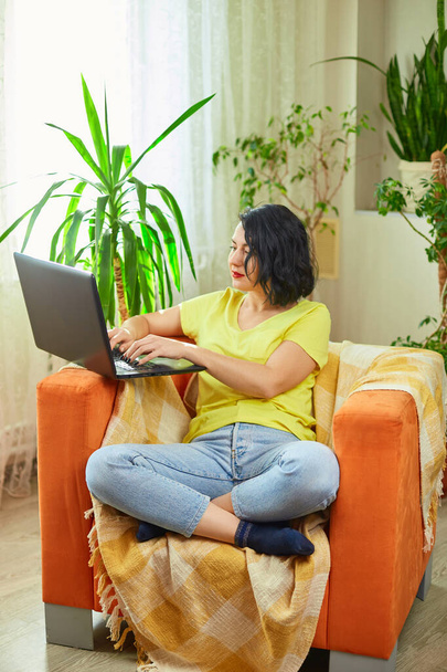 Woman freelancer working on laptop at home, Attractive female studying online, using laptop software, web surfing information or shopping in internet store, green house - Foto, Imagen