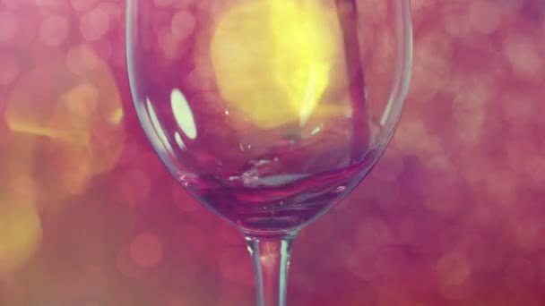 Pouring red wine into a glass with red sparkling background - 映像、動画