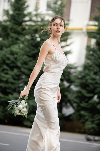 pretty woman in white dress holding wedding bouquet with blooming flowers  - Fotografie, Obrázek