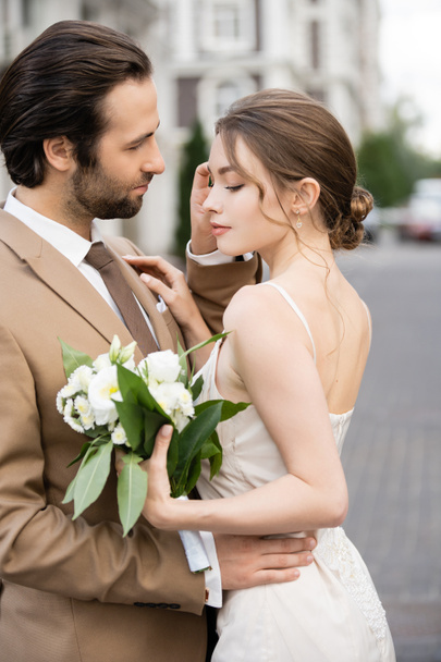 hübsche Braut im Brautkleid mit blühenden Blumen und Bräutigam  - Foto, Bild