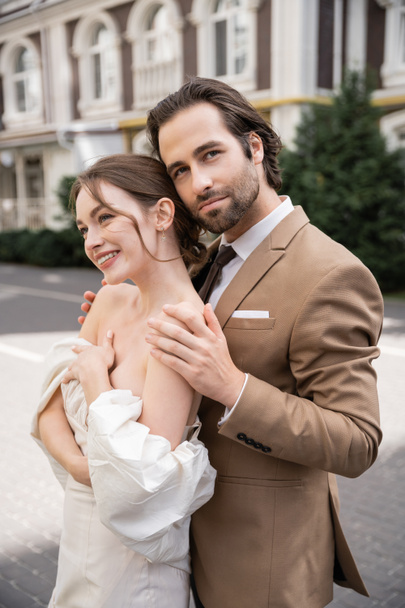 портрет бородатого чоловіка, який обіймає щасливу наречену у весільній сукні
  - Фото, зображення