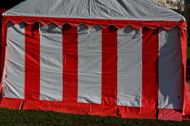 Sheets made of non-flammable materialPVC tarpaulin for trucks rear entrance equipped with zip windows made of transparent plastic Steel frame of the tent made of galvanized pipes, red, white stripes - Foto, imagen