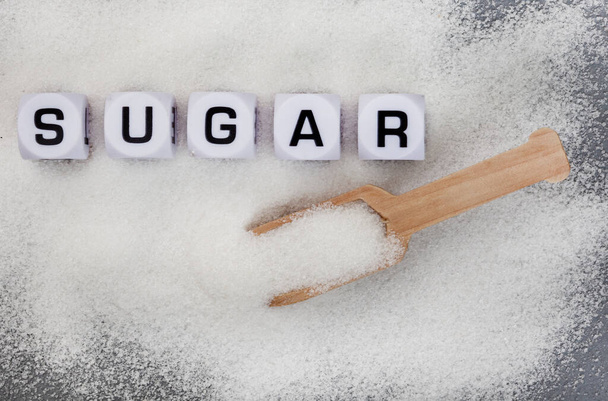 Sugar written in letter dice on white sugar granules - Foto, afbeelding