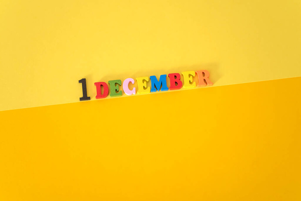 1. Dezember auf gelbem und papierfarbenem Hintergrund mit hölzernen und bunten Buchstaben mit Platz für Text. Konzept zum Welt-Aids-Tag. - Foto, Bild