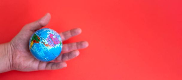 Globe in hand on red and paper background with space for text. The concept of love for the earth. - Fotó, kép