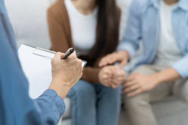 couple relationship therapy with a counselor. Close Up hands of the psychologist take notes on a clipboard during a conversation with clients to find problems and solution. - Foto, imagen