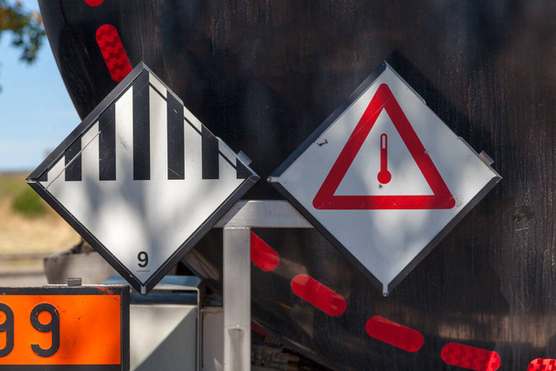 Dangerous goods signs on a tank truck back. The left placard indicate the good is a Hazardous Material and the right one that it is triggered when Elevated Temperature. - Photo, Image