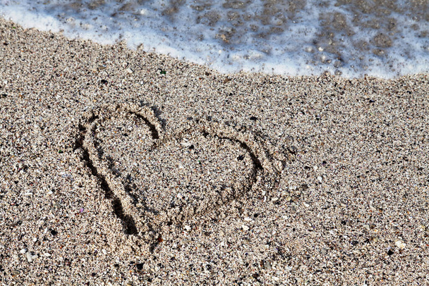Herz im Sand des Strandes von Saint-Pierre de la Réunion mit einer Welle, die es auslöschen wird. - Foto, Bild