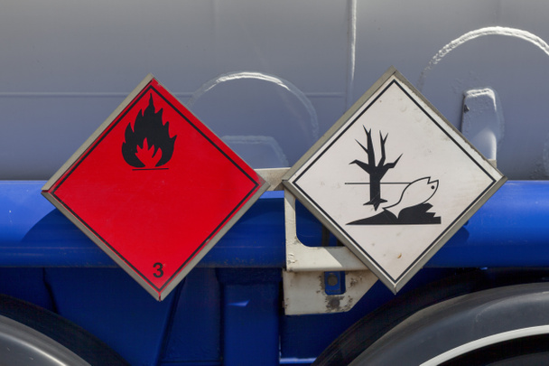 Tekenen van gevaarlijke goederen op een tankwagen. Het rode bordje geeft aan dat het goed een brandbare vloeistof is en dat het ook een milieugevaarlijke stof is.. - Foto, afbeelding