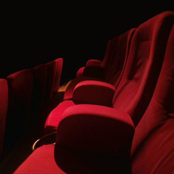 Ряды красных бархатных сидений в темноте и совершенно пустых. - Фото, изображение