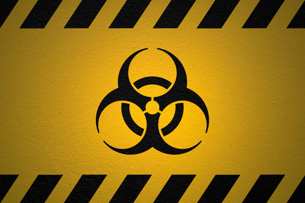Black striped yellow background with a Danger Biohazard sign and a light effect to dramatize the whole. - Foto, Imagem