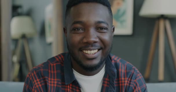 Portrait of positive young African American man smiling indoors in modern apartment looking at camera with happy face. Emotion and home concept. - Záběry, video