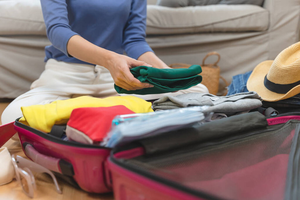 person prepare clothes and accessories to luggage before summer vacation trip. - 写真・画像