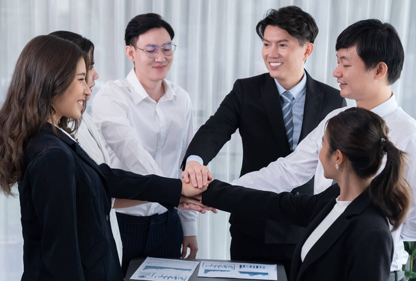 Closeup business team of suit-clad businessmen and women join hand stack together and form circle. Colleague collaborate and work together to promote harmony and teamwork concept in office workplace. - Photo, Image