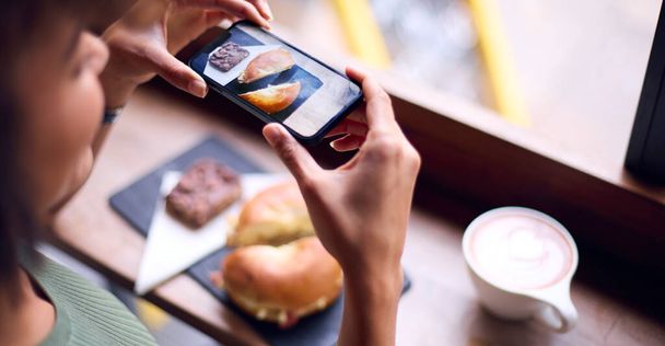 Donna in caffetteria Scattare foto di cibo da pubblicare sui social media - Foto, immagini
