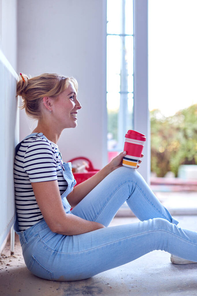 Woman Decorating Room At Home Sitting On Floor Taking A Break With Hot Drink In Reusable Cup - Photo, Image