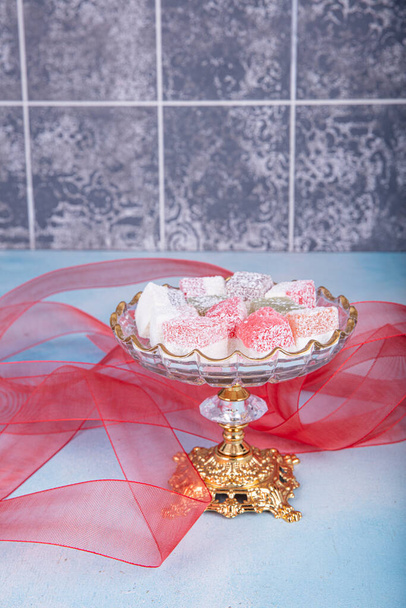 Assorted Turkish delights on glass candy stand. white wooden background. Eid catering concept. Close up. - Foto, Bild