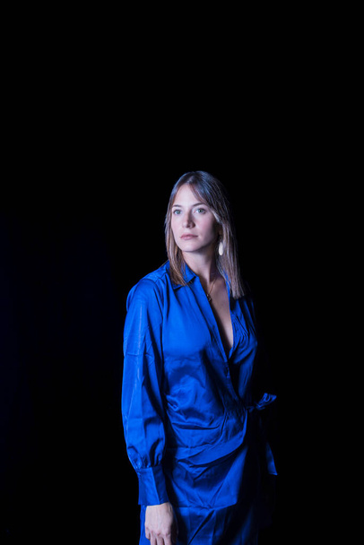 young woman dressed in a blue dress and black background looking straight ahead with a look of defiance and tranquility beauty photos - Foto, immagini