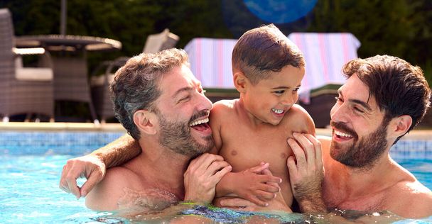 Однополые семьи с двумя отцами и сыном на отдыхе в бассейне вместе - Фото, изображение