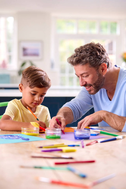 Mature Father At Home In Kitchen With Son Painting Picture Together - Фото, изображение
