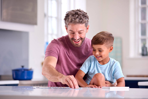 Зрілий батько вдома на кухні з сином робить головоломки разом
 - Фото, зображення