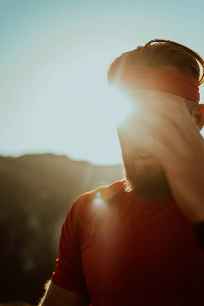 Atleta determinato che si prepara all'inizio dell'allenamento sulla cima della montagna all'alba - Foto, immagini