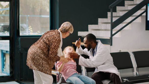 Afrikai-amerikai orvosi tanácsadó kislány szédül, a kórház várótermében ül és majdnem elájul. Aggódó nagyszülők gyermeket hoznak az egészségügyi intézménybe, eszméletlenek.. - Fotó, kép