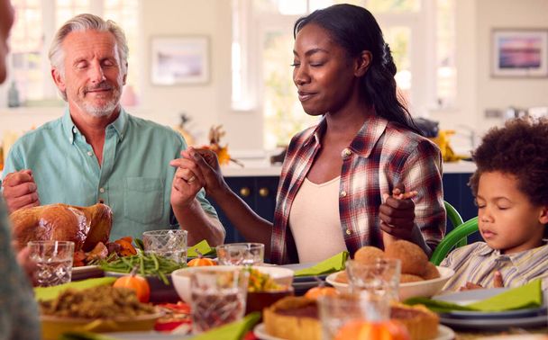一緒に食事をする前に祈る家庭で感謝祭を祝う多世代家族 - 写真・画像