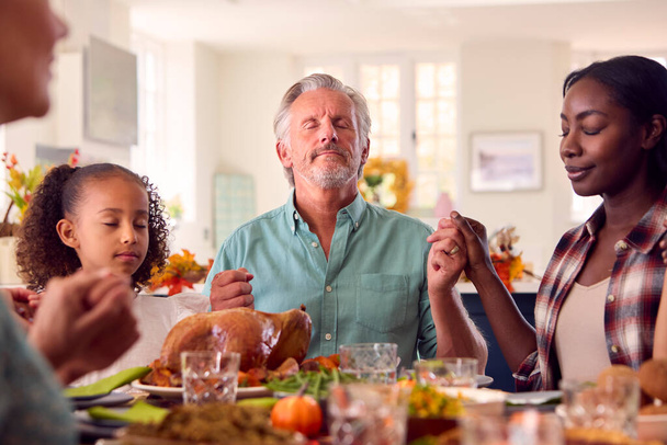 Több generációs család ünnepli a Hálaadást otthon imádkozva étkezés előtt együtt - Fotó, kép