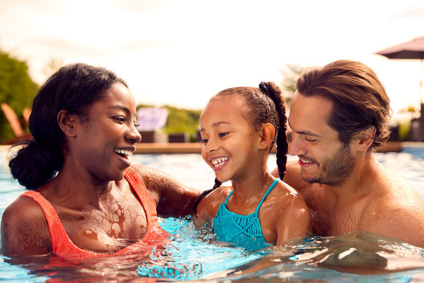 Smiling Mixed Race Family On Summer Holiday Having Fun Splashing In Outdoor Swimming Pool - Foto, immagini