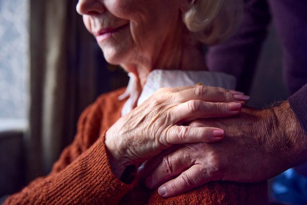 close-up van senior paar thuis met man zetten geruststellende hand op de schouder van de vrouw - Foto, afbeelding