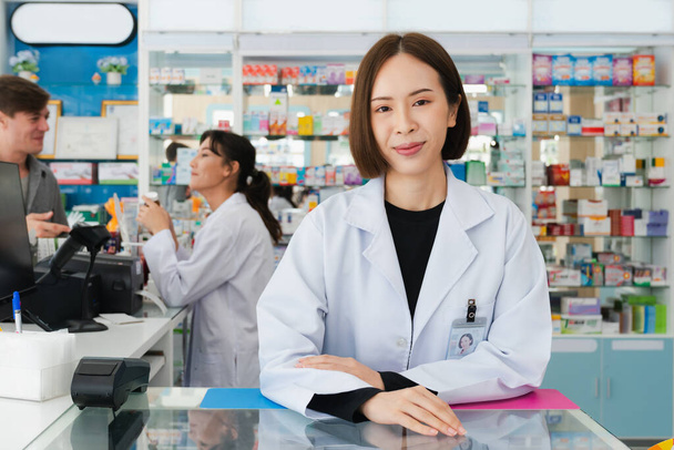 Portret zamożnego aptekarza azjatyckiego i wykwalifikowanego farmaceuty, butelka z lekami na półce w tle w aptece. Koncepcja farmaceuty pracującego nad kasjerem rozmawiającego z klientem w aptece. - Zdjęcie, obraz