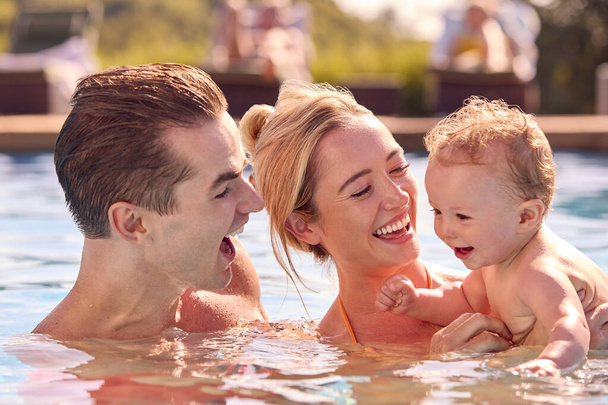 Smiling Family With Baby Son On Summer Holiday Playing In Swimming Pool - Valokuva, kuva