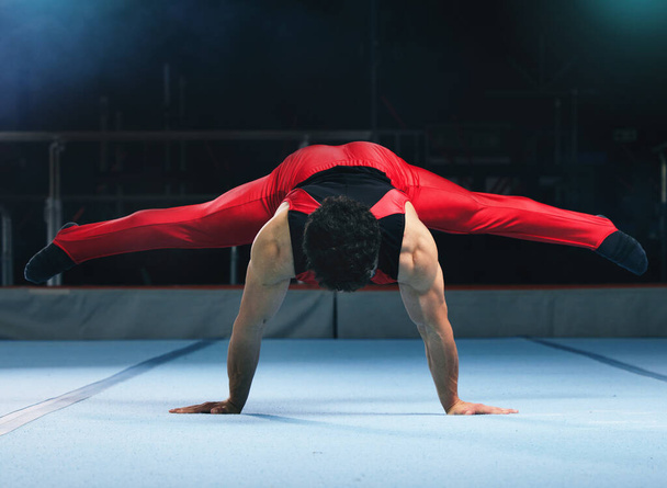 Gymnastics, handstand and man on gym floor for training, balance and wellness with muscle, strong body and night. Gymnast, athlete and exercise in studio for competition, goals and fitness for sport. - Foto, immagini