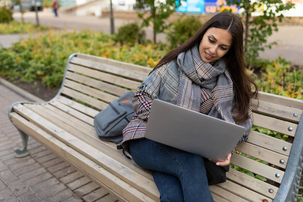 ενήλικη γυναίκα που εργάζεται σε φορητό υπολογιστή, ενώ κάθεται στο πάρκο. - Φωτογραφία, εικόνα