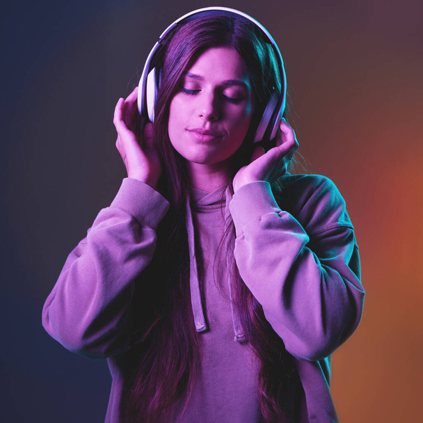 Müzik, neon ve gen z stüdyoda bir kadınla birlikte duvarda özgürlük için radyo dinliyor. Siber punk, kulaklıklar ve canlı müzik. Çekici genç bir kadın en iyi şarkısını dinliyor.. - Fotoğraf, Görsel