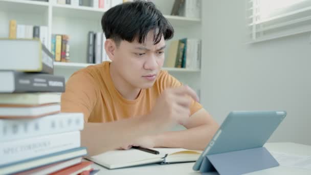 Азиатский студент изучает образец экзамена по таблицам, мужчина готовится к тестированию и занятиям в библиотеке. стресс, воздух, спешка, непонимание чтения, разочарование, отхаркивание, знание - Кадры, видео