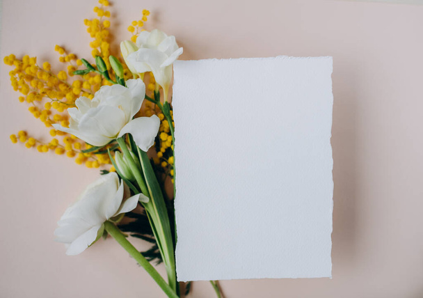 white paper mockup with texture on festive peach background with flowers white and yellow colors,wedding invitation mockup, top view, spring mockup - 写真・画像