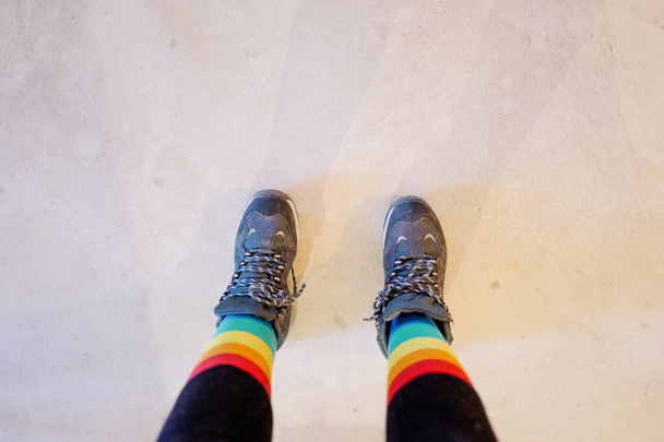 downward self portrait of feet with lgtb socks and hiking boots, copy space. close-up view of person in tights, rainbow socks and walking boots. - Valokuva, kuva