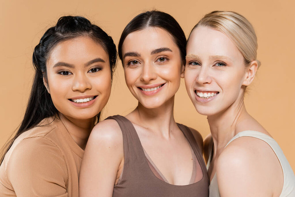 pretty multiethnic women in lingerie smiling at camera isolated on beige - Foto, Imagem