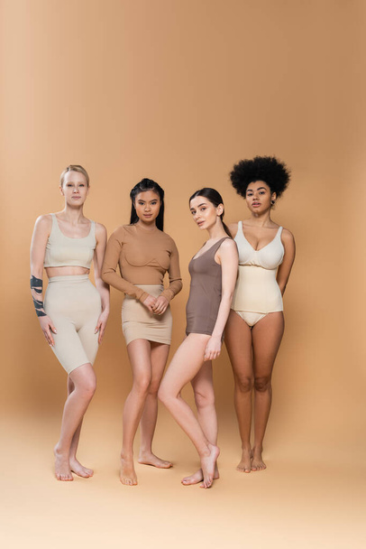 full length of barefoot multiethnic women in underwear standing on beige background - Zdjęcie, obraz