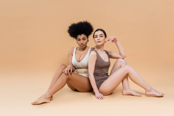 full length of barefoot interracial women in lingerie posing on grey background - Photo, Image