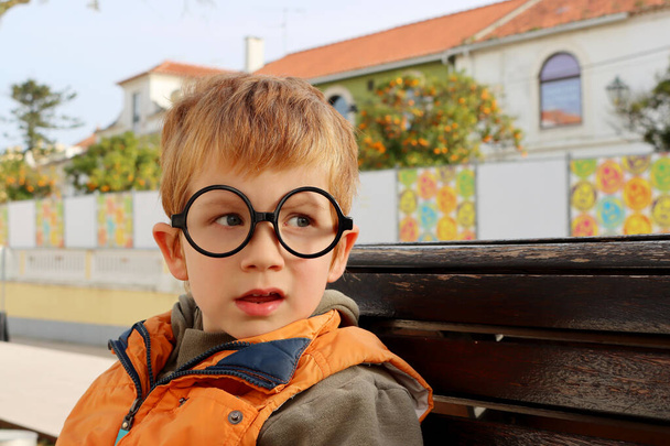 おもちゃの眼鏡をかけた金髪の少年が興味津々の側面に目を向ける。面白い5歳の男の子. - 写真・画像