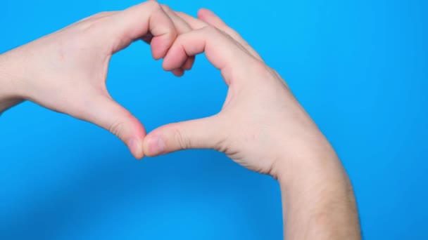 Close-up de uma mão de homem fazendo um gesto em forma de coração, isolado em um fundo cromado tela azul. Uma pessoa forma um coração com a ajuda de dedos. Fechar - Filmagem, Vídeo