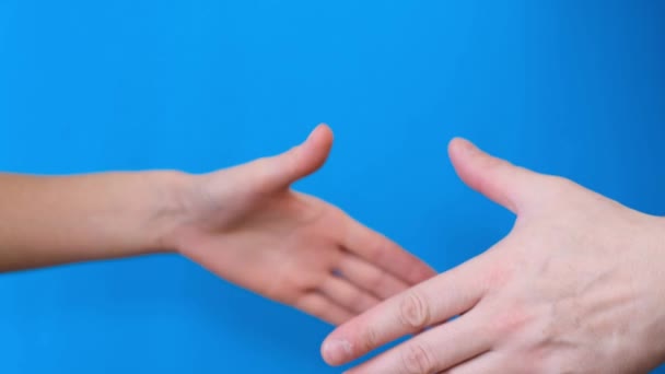 Primo piano di un uomo e una donna che si tengono per mano nel saluto su uno sfondo blu. 4k video - Filmati, video